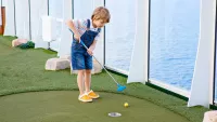 Boy playing mini golf min