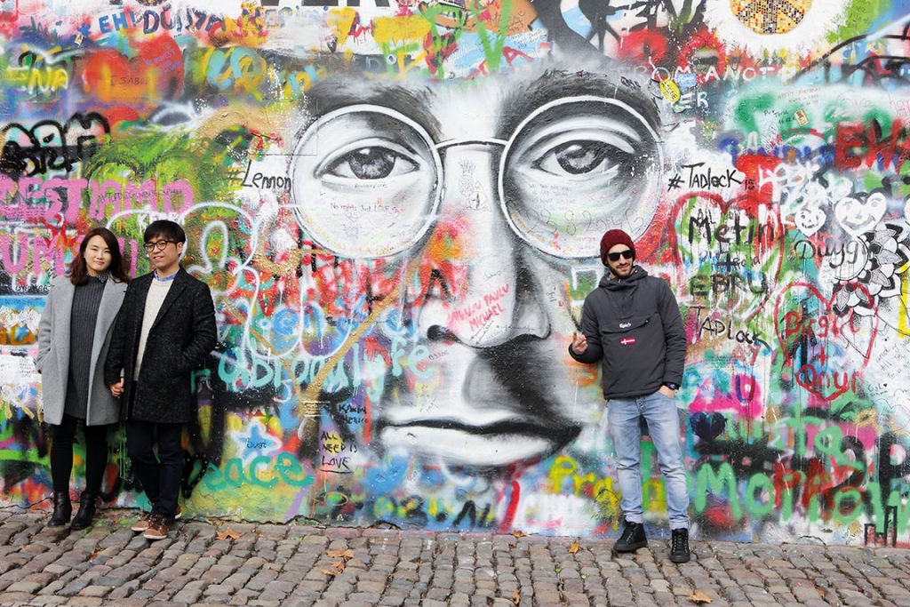 Tourists pose by the John Lennon graffiti wall in Prague city