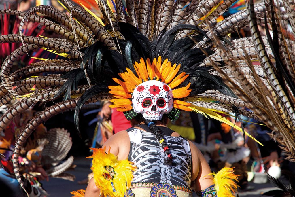 Man dressed in skull costume and feathers at Mexico festival